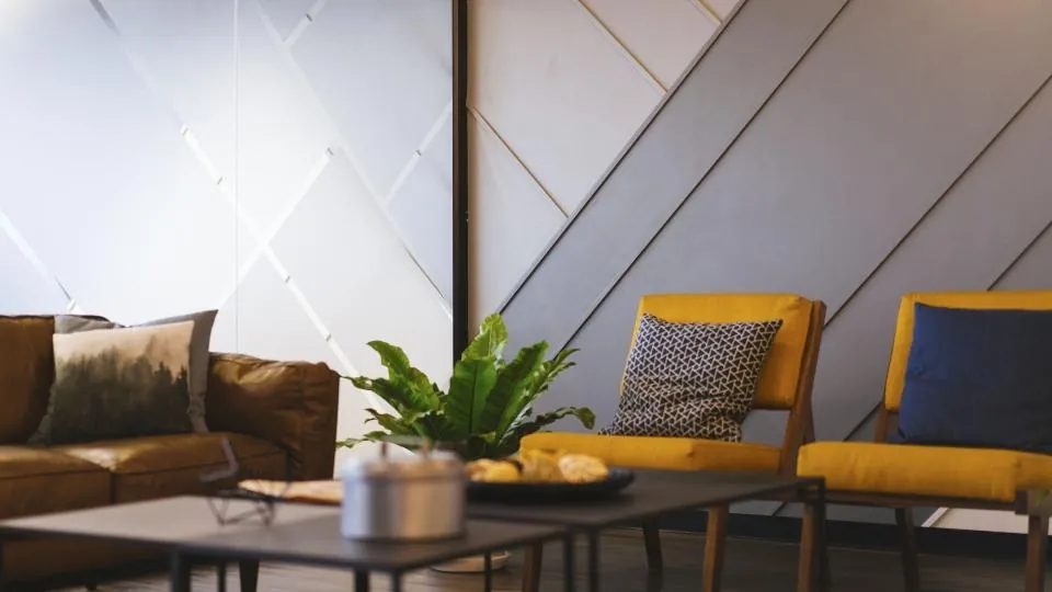 A corner with a brown sofa, two yellow armchairs and a low table with a plant.