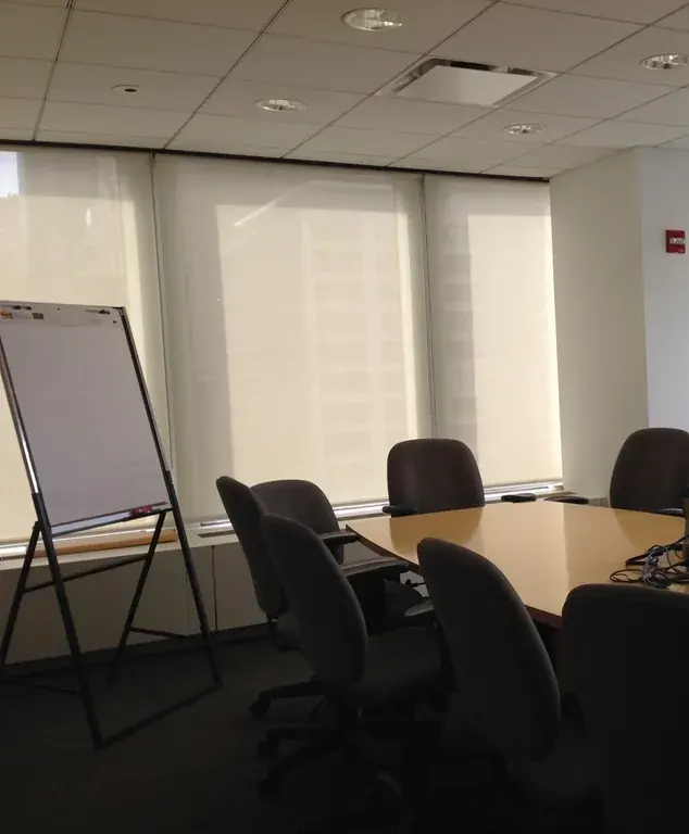 A smaller room with a long table, chairs and a flip chart by a big window.