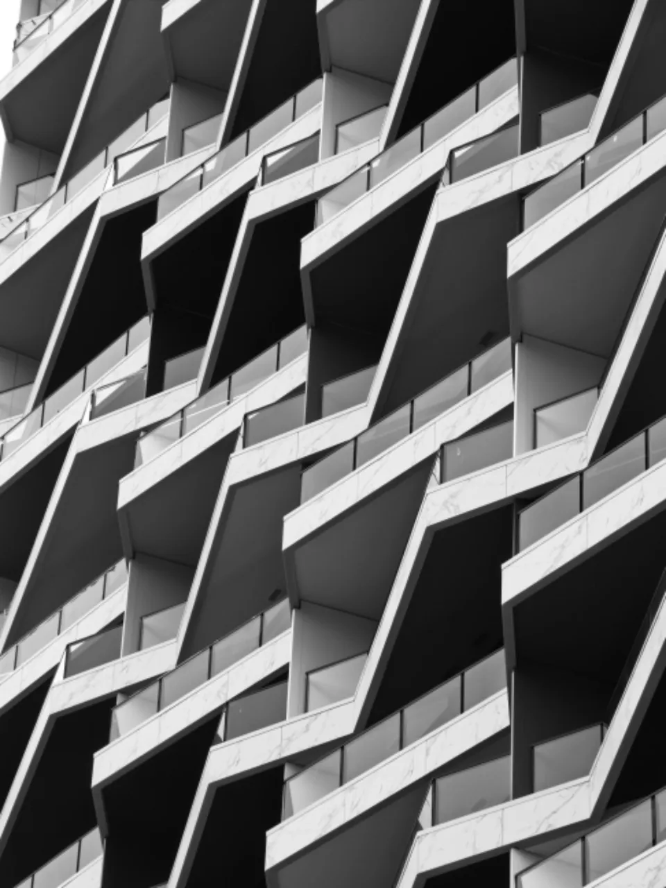 Rows of angled concrete balconies on an apartment block, in black and white.