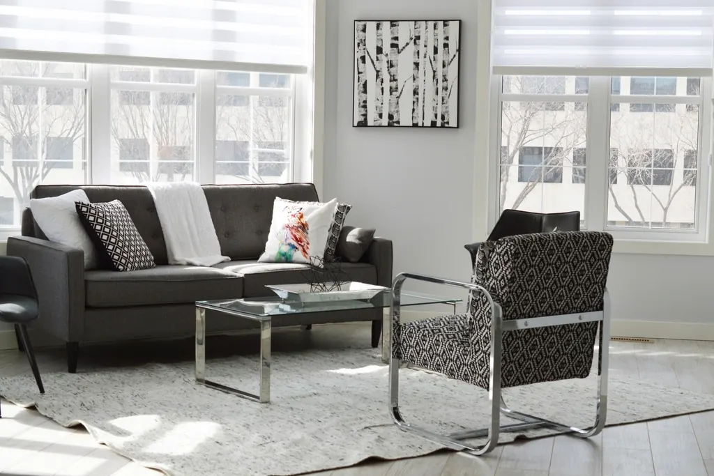A light living room with a dark sofa, an armchair and a wall of windows.