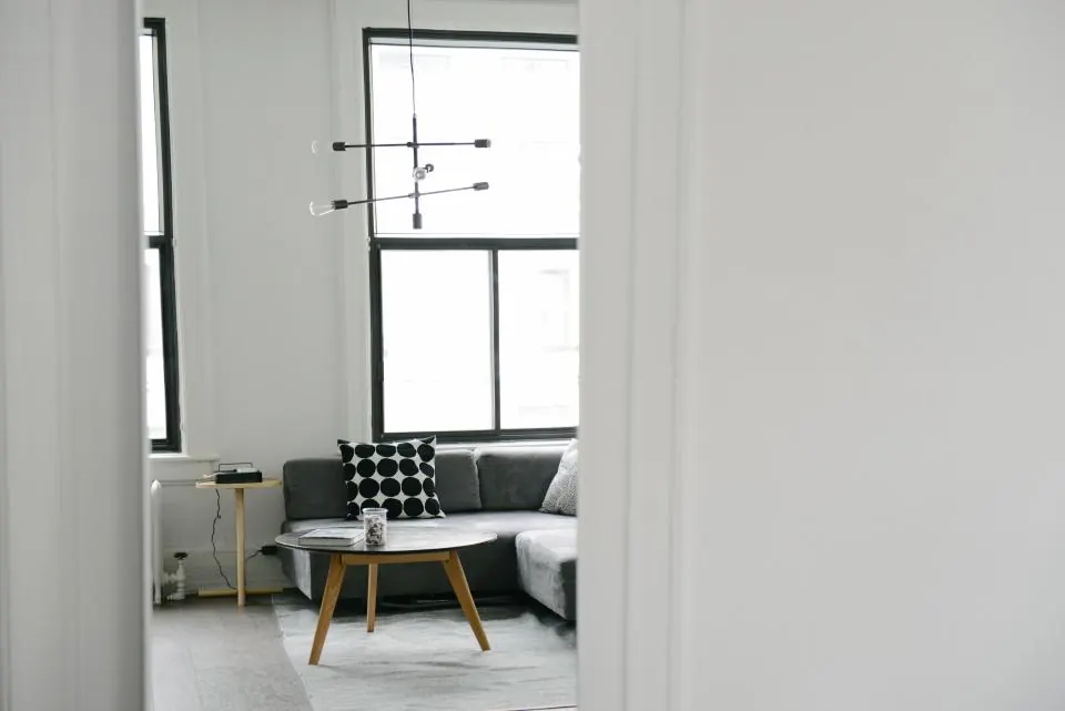 The second reception room: a dark sofa and a small round table by a tall window.