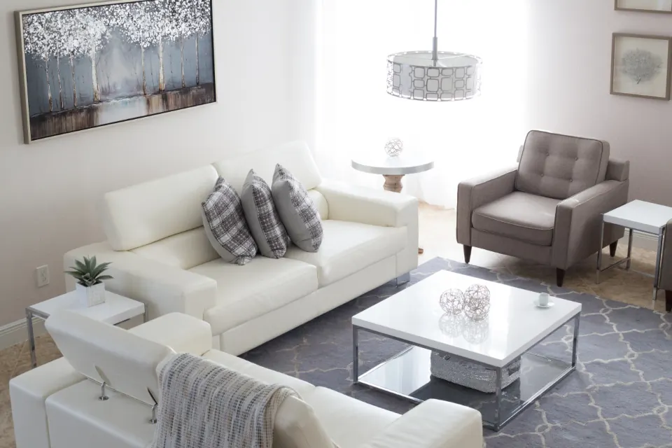 A living room with a white sofa, a grey armchair and a square coffee table.
