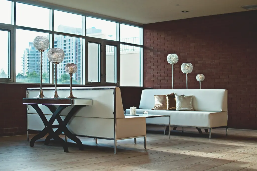 A bright open-plan living room with large windows and a brick wall.