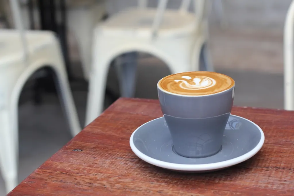 A cup of flat white with latte art on a wooden table.