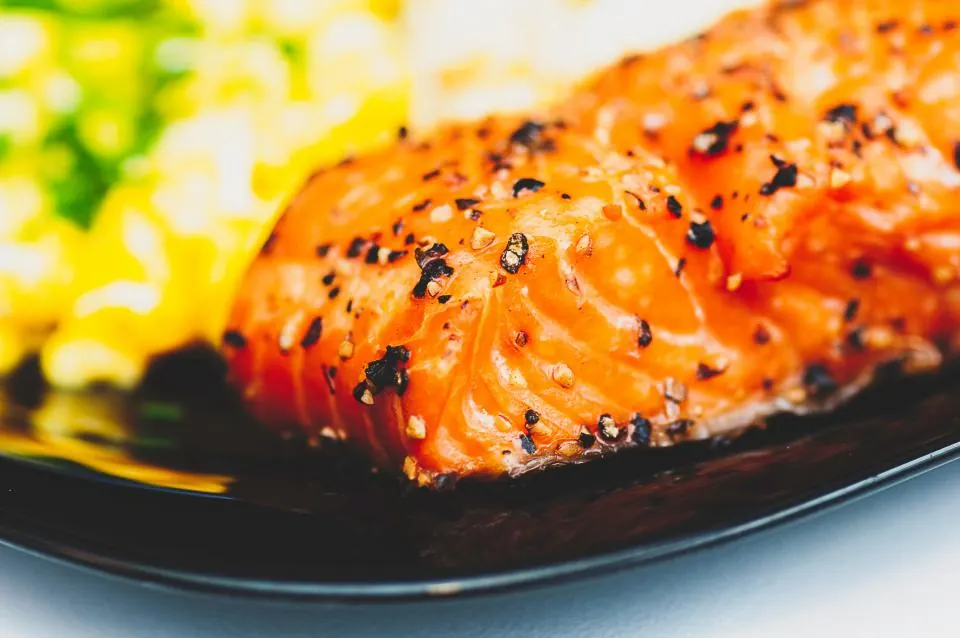 A seared salmon fillet with sesame seeds and a dark glaze.