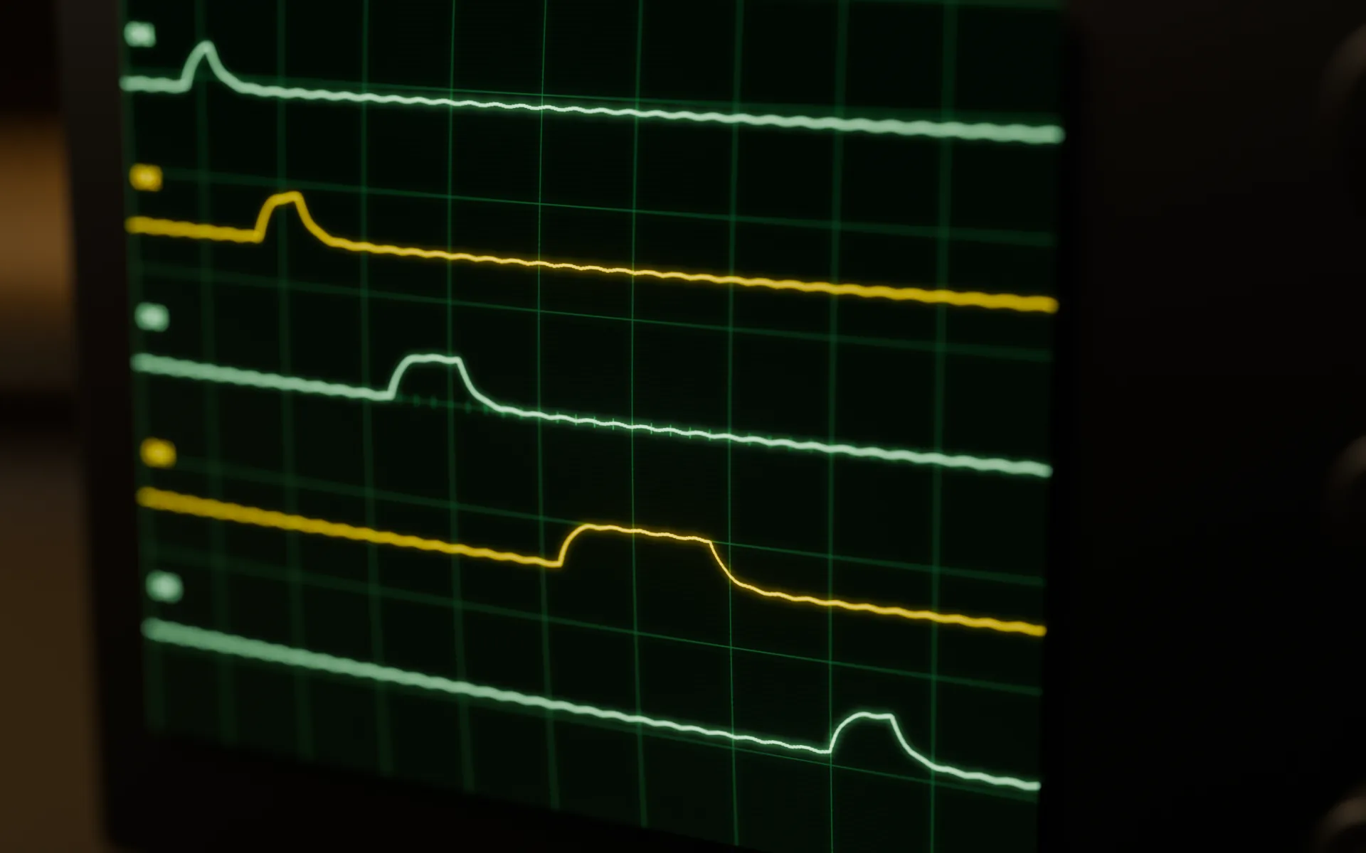 Close-up of the bench oscilloscope's screen: a green graticule with five amber and green traces.